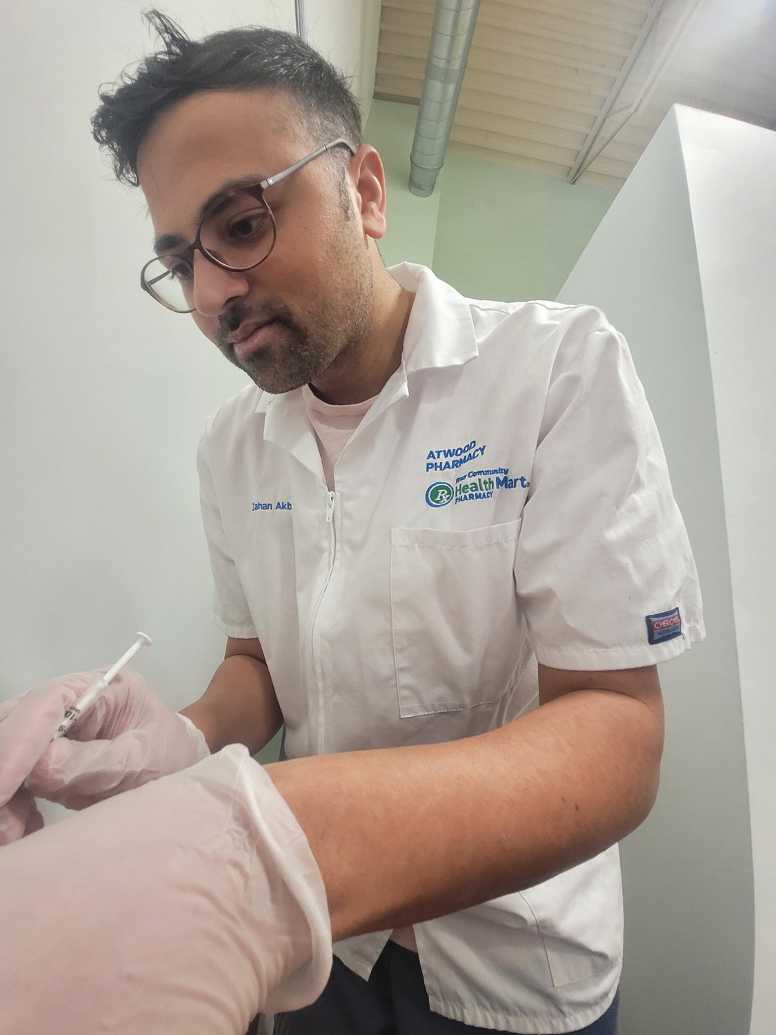 IMMUNITY BOOSTER: Zahan Akbar, owner of the Atwood Pharmacy, has watched demand for COVID-19 tests, vaccines and booster shots climb quickly over the past few weeks. Akbar holds a Phizer booster shot, moments before delivering it.